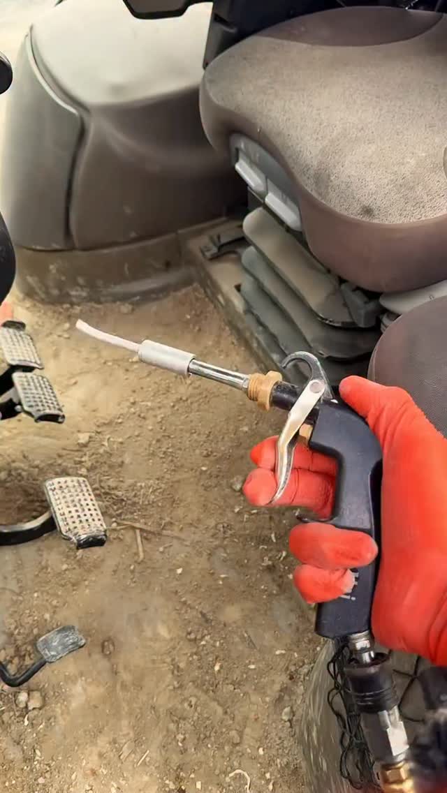 Air cleaning gun aimed at a floor covered in dirt and sand next to the pedals