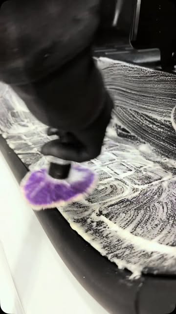 Drill brush scrubbing foam across a black rubber floor liner